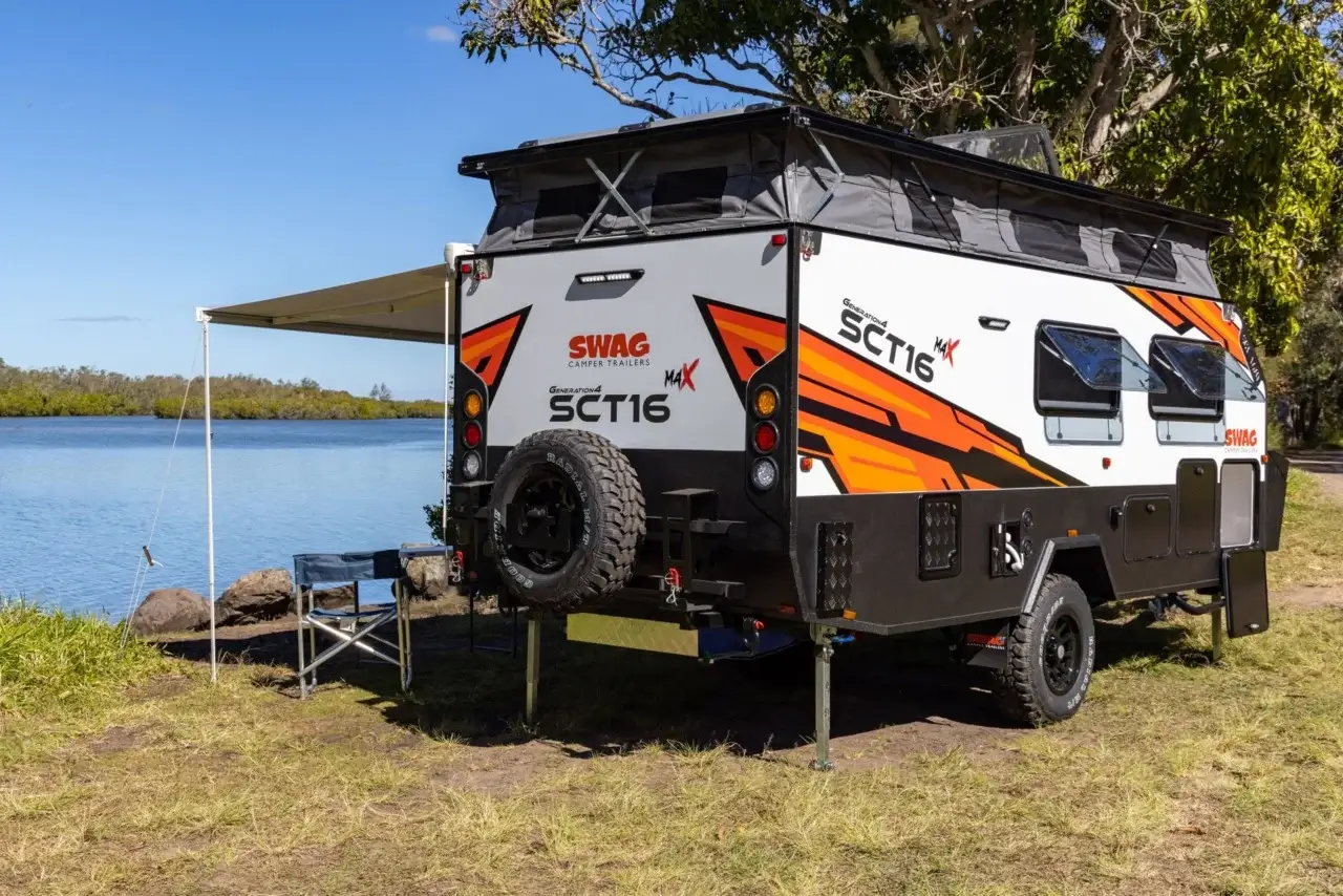 SWAG hybrid pop-top caravan with roof raised at a riverside campsite